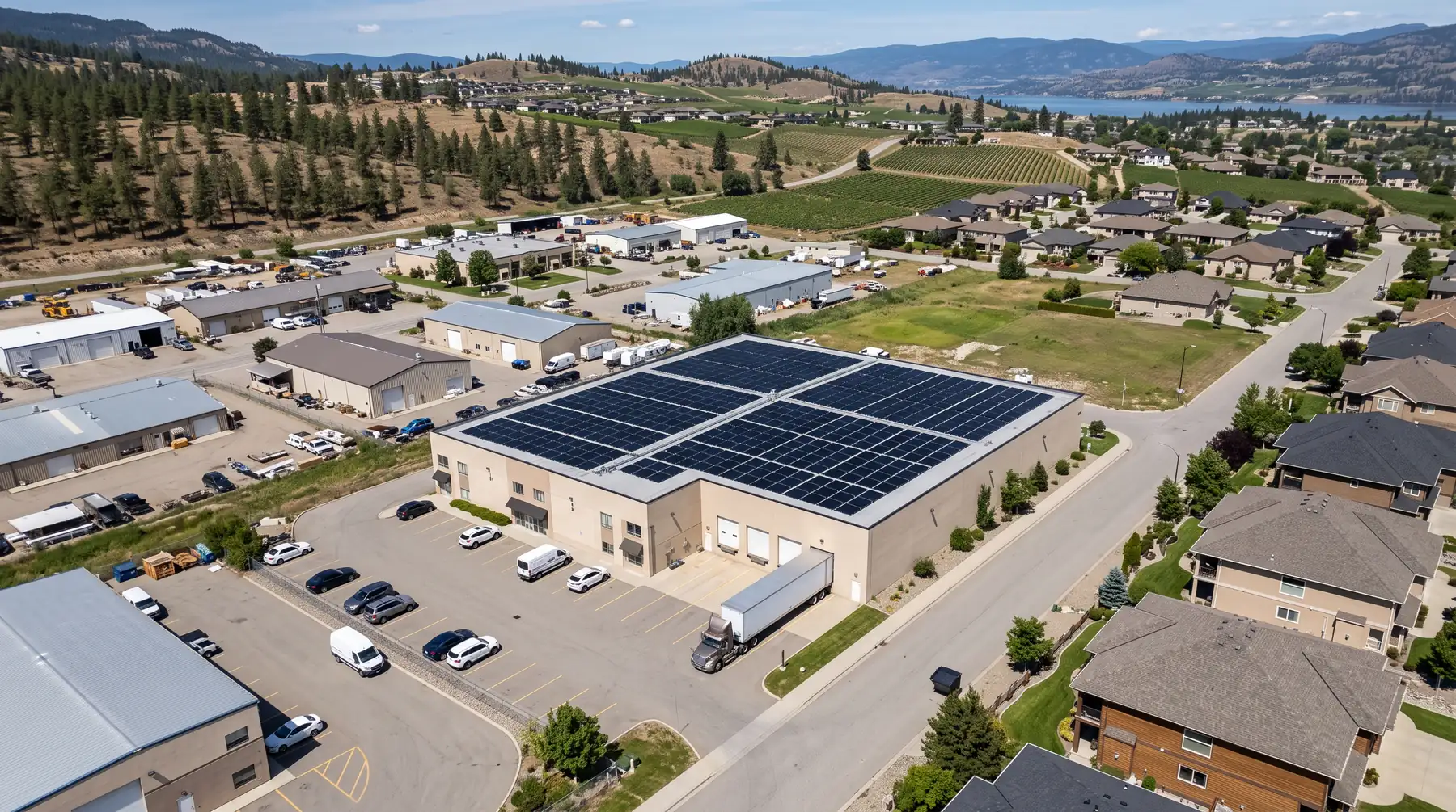 Aerial view of a light-industrial building in Kelowna with a large solar array covering its flat roof